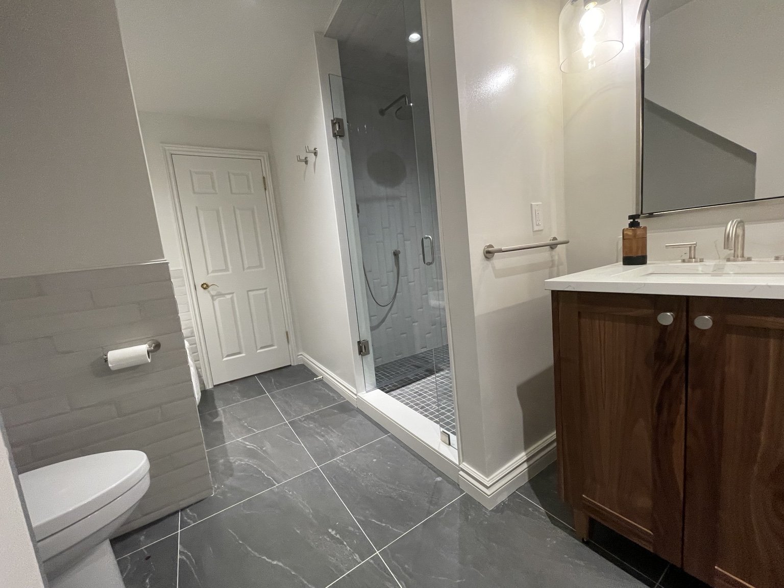 A warm wood vanity, glass shower and a simpler palette.