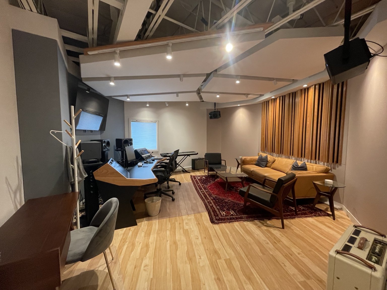 Completed sound studio with overhead acoustic panels, timber slat wall and recording desk